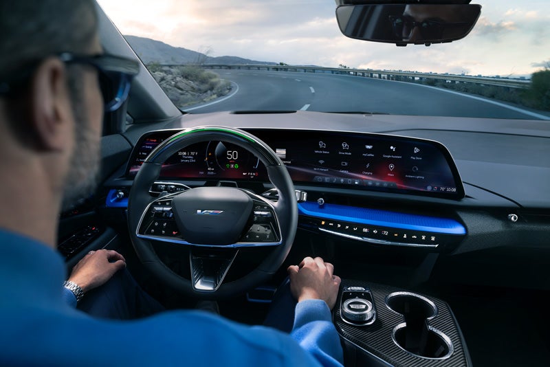 Front View of the 2026 OPTIQ-V Driving Through the Dusk Utilizing its Headlights | Les Stanford Cadillac in Dearborn MI