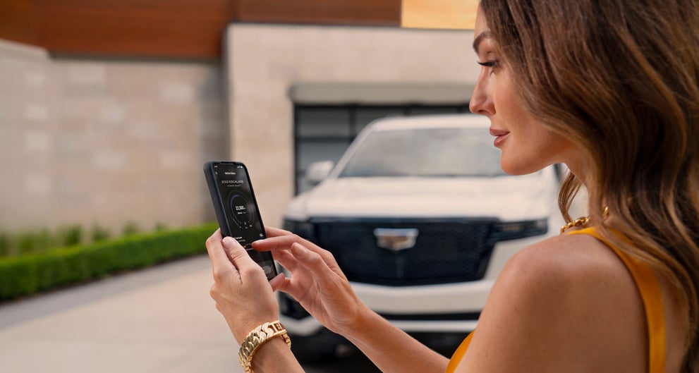 lady checking her mobile with a Cadillac vehicle background | Les Stanford Cadillac in Dearborn MI